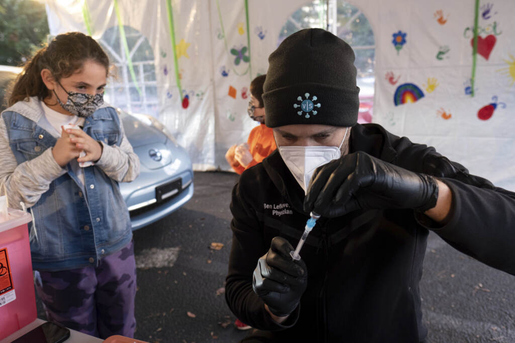 Virus Outbreak Kids Vaccine Leah Lefkove, 9, waits as her dad Dr. Ben Lefkove prepares the first COVID-19 vaccine for her at the Viral Solutions vaccination and testing site in Decatur, Ga., on the first day COVID-19 vaccinations were available for children from 5 to 12 on Wednesday, Nov. 3, 2021. The U.S. enters a new phase Wednesday in its COVID-19 vaccination campaign, with shots now available to millions of elementary-age children in what health officials hailed as a major breakthrough after more than 18 months of illness, hospitalizations, deaths and disrupted education. (AP Photo/Ben Gray)