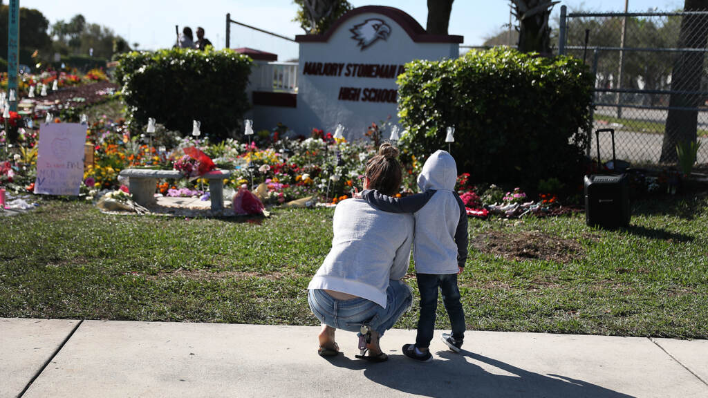 A memorial is seen outside Marjory Stoneman Douglas High School in Parkland, Fla., in honor of those killed during a 2018 mass shooting. Families of more than a dozen victims have reached a legal settlement with the Justice Department. A memorial is seen outside Marjory Stoneman Douglas High School
