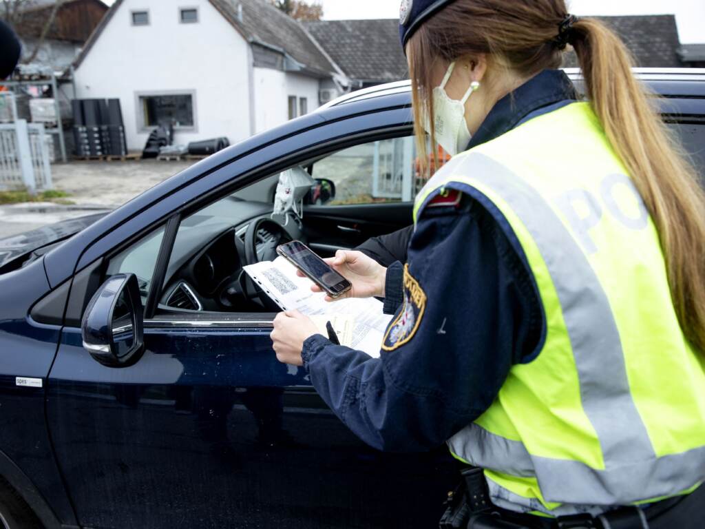 An Austrian police officer checks a driver’s vaccination certificate during a traffic control stop in Graz, Austria, on Monday. An Austrian police officer checks a driver's vaccination certificate