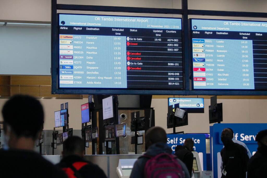 Travellers walk near an electronic flight notice board displaying cancelled flights  at OR Tambo International Airport in Johannesburg on November 27, 2021, after several countries banned flights from South Africa following the discovery of a new Covid-19 variant Omicron. - A flurry of countries around the world have banned ban flights from southern Africa following the discovery of the variant, including the United States, Canada, Australia,Thailand, Brazil and several European countries. The main countries targeted by the shutdown include South Africa, Botswana, eSwatini (Swaziland), Lesotho, Namibia, Zambia, Mozambique, Malawi and Zimbabwe. (Photo by Phill Magakoe / AFP) (Photo by PHILL MAGAKOE/AFP via Getty Images)
