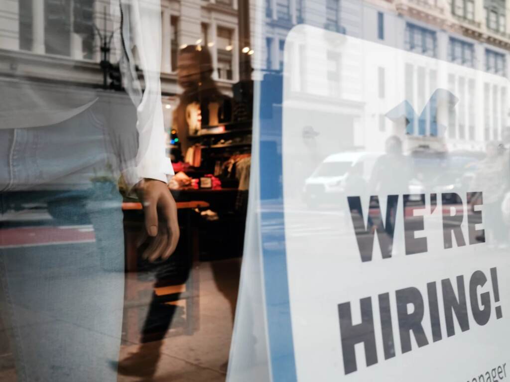People walk by a hiring sign in a store window in New York on Nov. 17. NEW YORK, NEW YORK - NOVEMBER 17: People walk by a hiring sign in a window along a main shopping street in Manhattan on November 17, 2021 in New York City. As Americans begin their holiday shopping early this year in an effort to avoid shortages of some goods, U.S. retail sales surged 1.7% last month, the largest gain since March