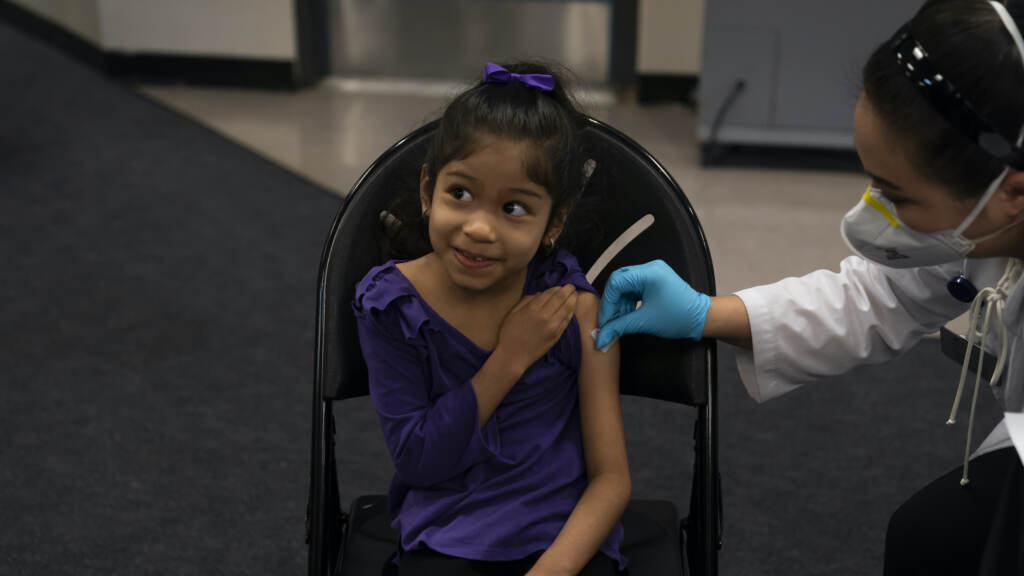 Elsa Estrada smiles as a pharmacist applies an alcohol swab to her arm