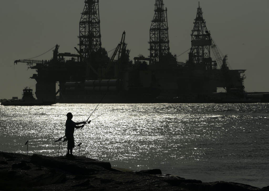 Biden Oil and Gas Leases A man wears a face mark as he fishes near docked oil drilling platforms