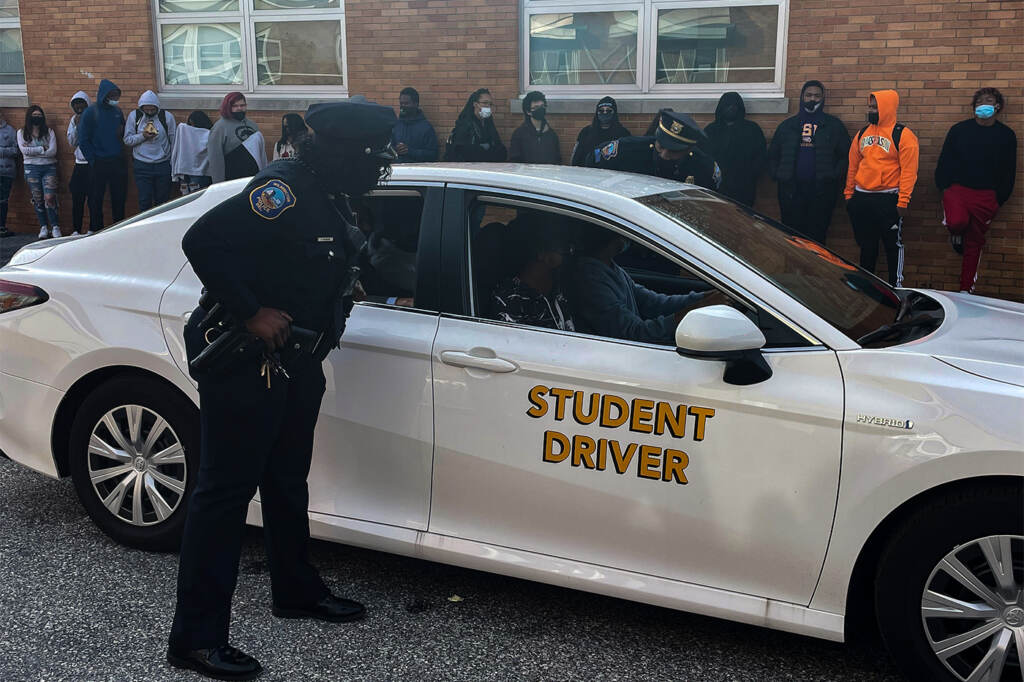 stop-1 A Wilmington police officer approaches a car with teen drivers during a simulation witnessed by other students at William Penn High School. (Cris Barrish/WHYY)