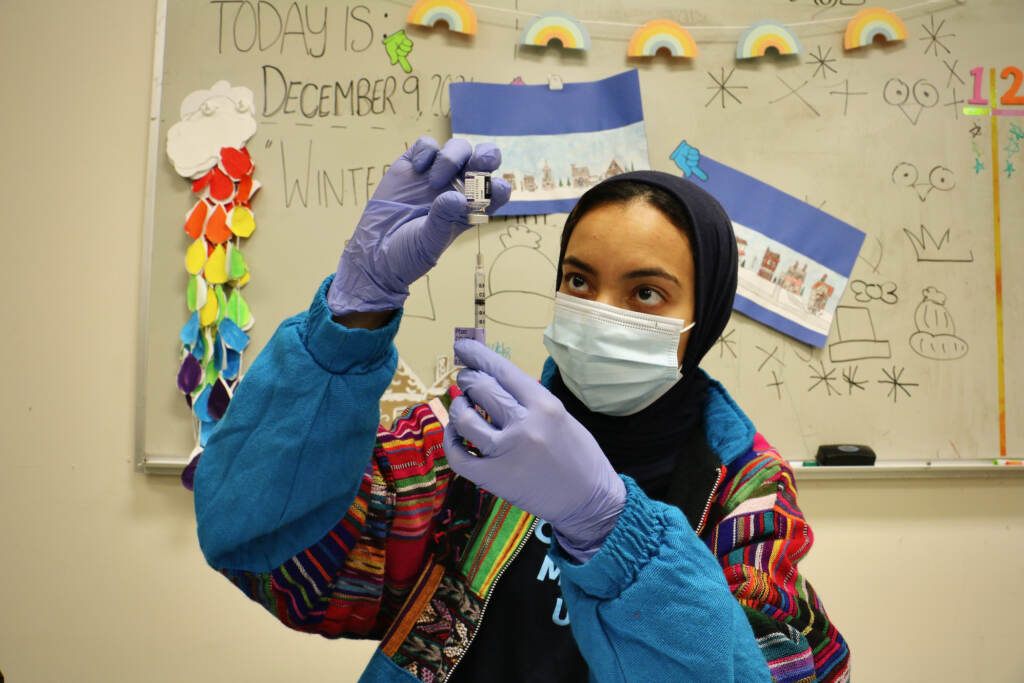2021 12 09-e lee-hajar mokhlis-philadelphia universal institute charter school-mobile covid 19 vaccine clinic 1 Dr. Hajar Mokhlis, a pharmacist with the Jefferson COVID-19 mobile unit, prepares vaccine doses in the art room at Universal Institute Charter School in South Philadelphia