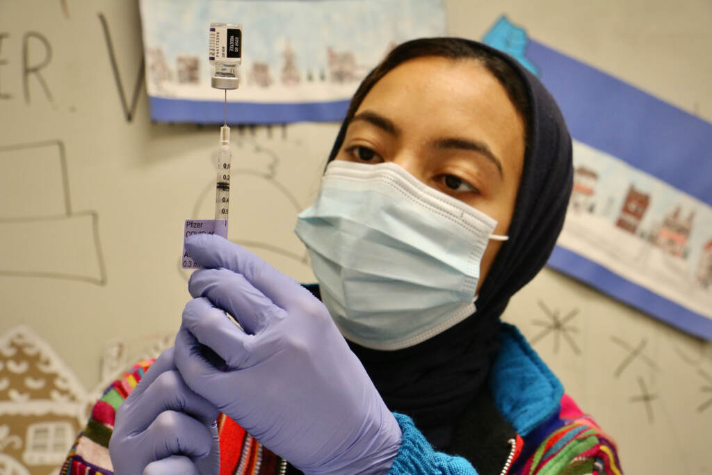 2021 12 09-e lee-hajar mokhlis-philadelphia universal institute charter school-mobile covid 19 vaccine clinic 2 Dr. Hajar Mokhlis, a pharmacist with the Jefferson COVID-19 mobile unit, prepares vaccine doses in the art room at Universal Institute Charter School in South Philadelphia