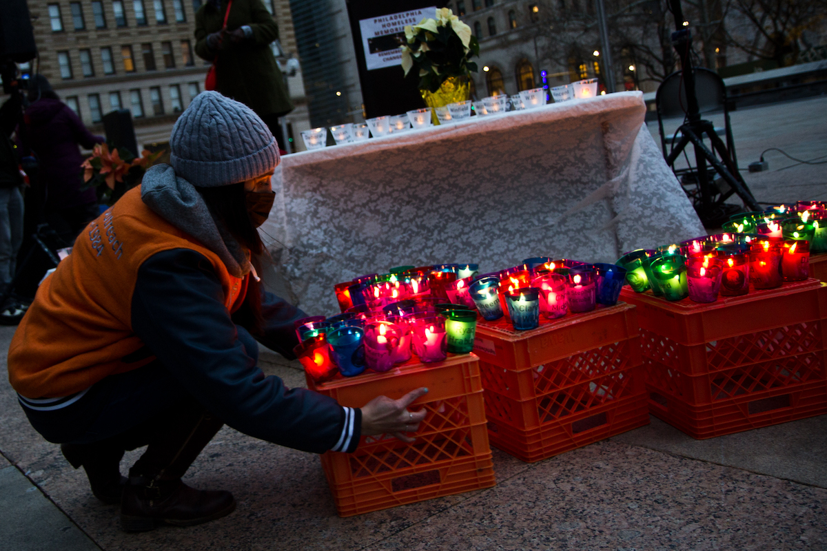 A Homeless Outreach worker places crates of votives with names in front of the lectern at Homeless Memorial Day on Dec. 21, 2021