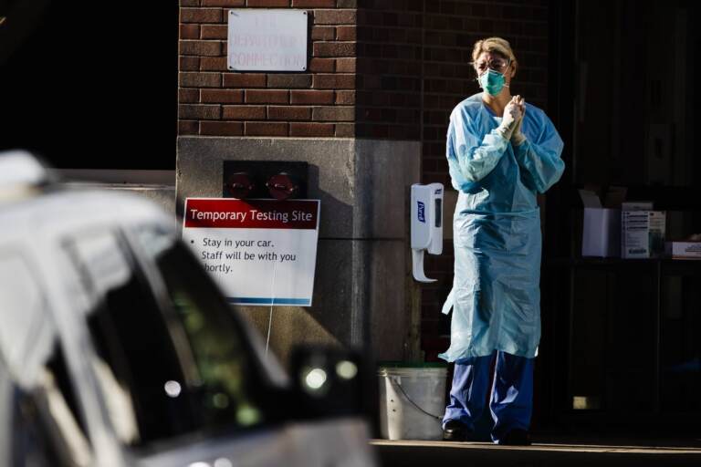 A healthcare worker stands by at a COVID-19 temporary testing site at Abington Hospital in Abington, Pa., Wednesday, March 18, 2020. For most people, the new coronavirus causes only mild or moderate symptoms. For some it can cause more severe illness. (AP Photo/Matt Rourke)

