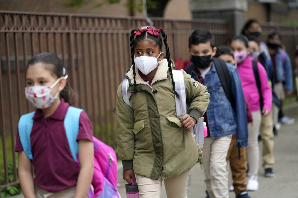 In this April 29, 2021, file photo, students line up to enter Christa McAuliffe School in Jersey City, N.J. Children are having their noses swabbed or saliva sampled at school to test for the coronavirus. As more children return to school buildings this spring, widely varying approaches have emerged on how and whether to test students and staff members for the virus.