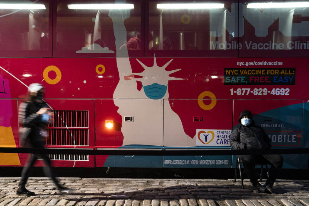 Virus Outbreak New York A mobile COVID-19 vaccination and booster shot site operates out of a bus on 59th Street south of Central Park as patients wait on the sidewalk, Thursday, Dec. 2, 2021, in New York. Health officials say multiple cases of the omicron coronavirus variant have been detected in New York, including a man who attended an anime convention in Manhattan in late November and tested positive for the variant when he returned home to Minnesota. (AP Photo/John Minchillo)