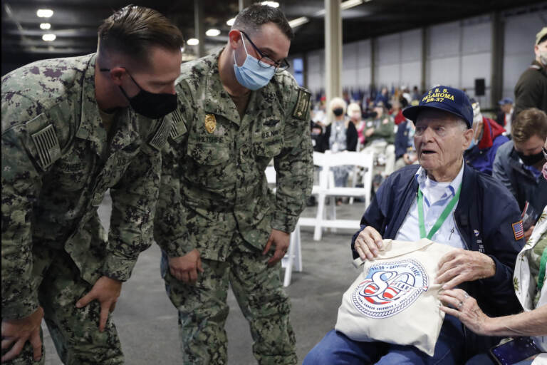 Pearl Harbor survivor and World War II Navy veteran David Russell, 101, of Albany, NY, shows off his commemorative bag to two military personnel before the start of the 80th Pearl Harbor Anniversary ceremony at Joint Base Pearl Harbor-Hickam, Tuesday, Dec. 7th, 2021, in Honolulu