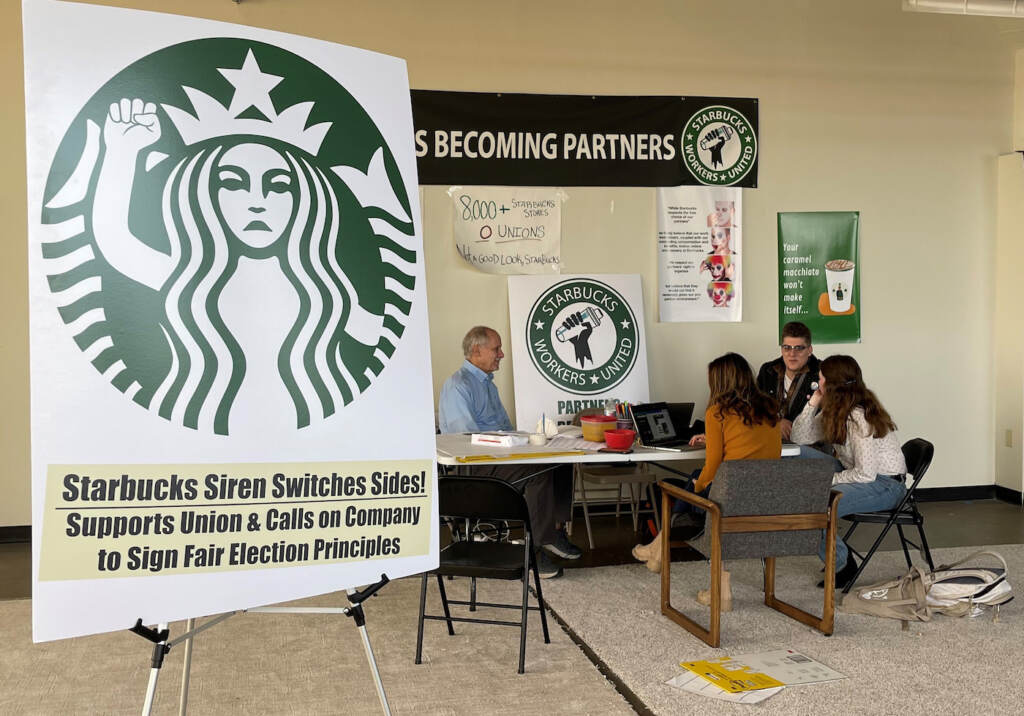 Starbucks Union Vote FILE- Richard Bensinger, left, who is advising unionization efforts, along with baristas Casey Moore, right, Brian Murray, second from left, and Jaz Brisack, second from right, discuss their efforts to unionize three Buffalo-area stores, inside the movements headquarters on Oct. 28, 2021 in Buffalo, N.Y. The National Labor Relations Board is scheduled to count ballots Thursday, Dec. 9, 2021, from union elections held at three separate Starbucks stores in the Buffalo area. Around 111 Starbucks workers from the three stores were eligible to vote by mail starting last month.(AP Photo/Carolyn Thompson, File)