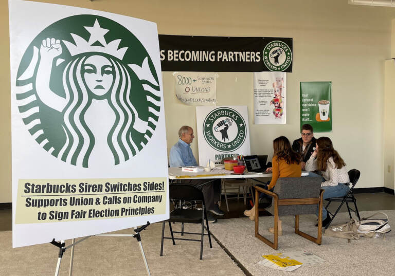 FILE- Richard Bensinger, left, who is advising unionization efforts, along with baristas Casey Moore, right, Brian Murray, second from left, and Jaz Brisack, second from right, discuss their efforts to unionize three Buffalo-area stores, inside the movements headquarters on Oct. 28, 2021 in Buffalo, N.Y. The National Labor Relations Board is scheduled to count ballots Thursday, Dec. 9, 2021, from union elections held at three separate Starbucks stores in the Buffalo area. Around 111 Starbucks workers from the three stores were eligible to vote by mail starting last month.(AP Photo/Carolyn Thompson, File)