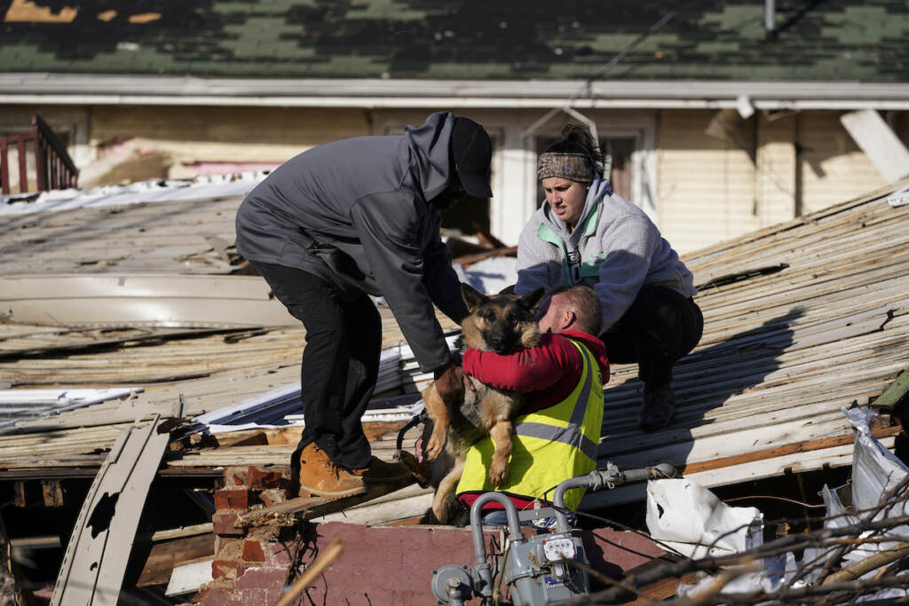 Dog owner Derrick Starks, left, Chris Buchanan, center and Niki Thompson, right, both from neighboring counties, attempt to rescue Cheyenne, the dog, from a tornado damaged home in Mayfield, Ky., on Saturday, Dec. 11, 2021. Tornadoes and severe weather caused catastrophic damage across multiple states Friday, killing several people overnight