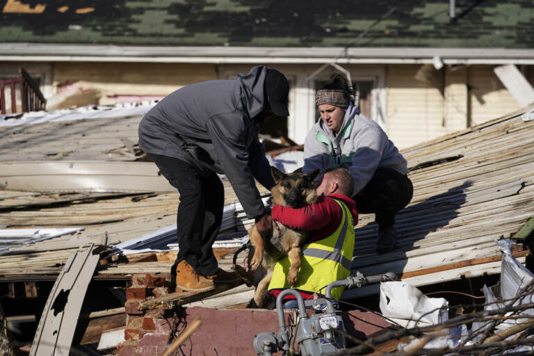 Dog owner Derrick Starks, left, Chris Buchanan, center and Niki Thompson, right, both from neighboring counties, attempt to rescue Cheyenne, the dog, from a tornado damaged home in Mayfield, Ky., on Saturday, Dec. 11, 2021. Tornadoes and severe weather caused catastrophic damage across multiple states Friday, killing several people overnight