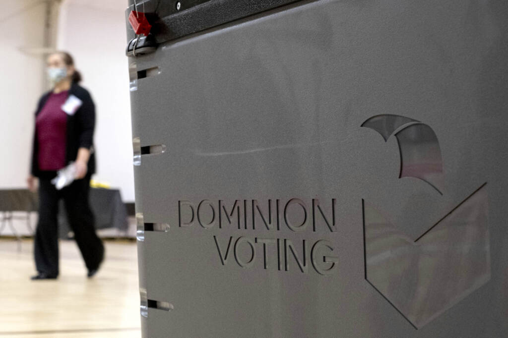 Voting Machines Rural County File photo: A worker passes a Dominion Voting ballot scanner while setting up a polling location at an elementary school in Gwinnett County, Ga., outside of Atlanta on Jan. 4, 2021. (AP Photo/Ben Gray, File)