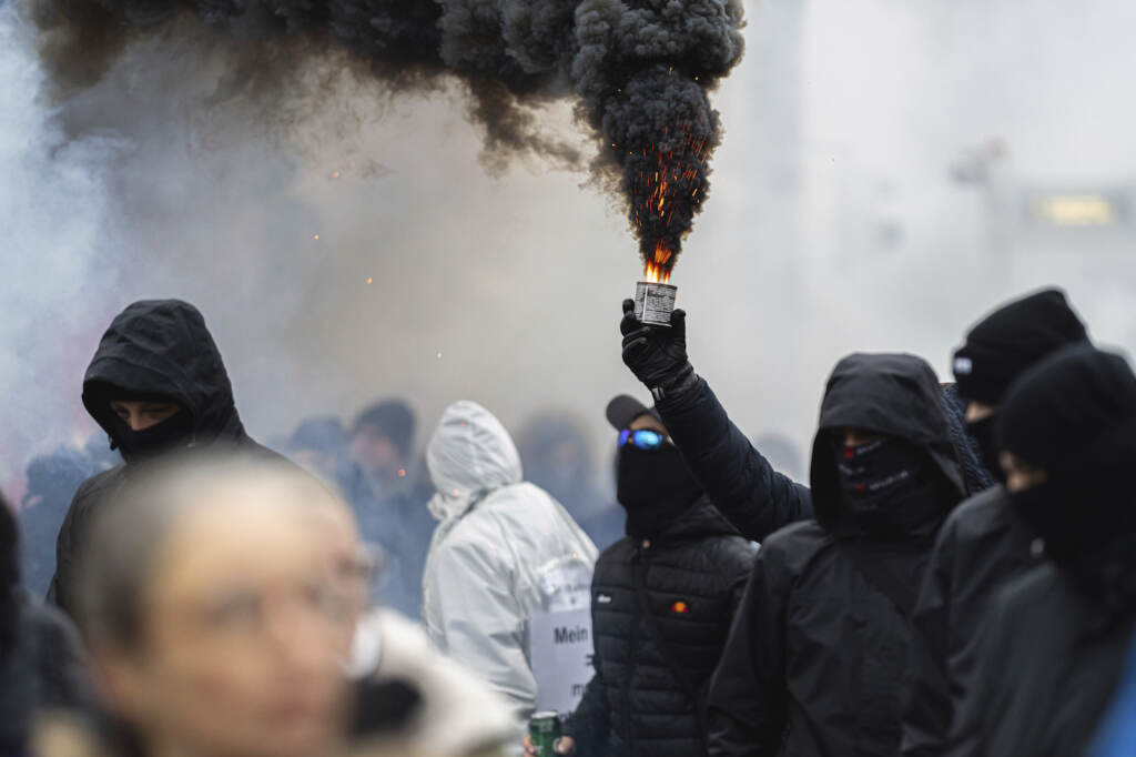 FILE - Protestors light flares during a demonstration against measures to battle the coronavirus pandemic in Vienna, Austria, on Dec. 11, 2021. New research indicates that far-right extremists and white supremacists are gaining new followers and influence by co-opting conspiracy theories about COVID-19.  (AP Photo/Florian Schroetter, File)