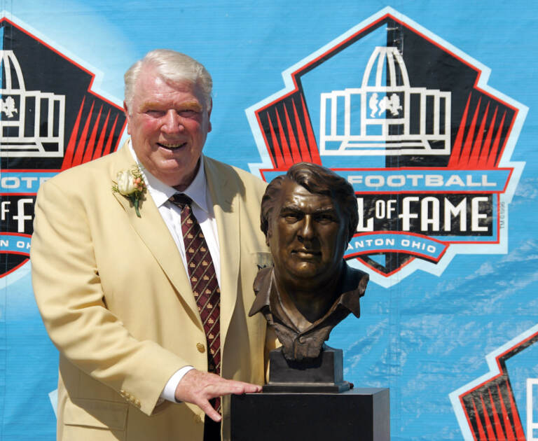 File Photo: Broadcaster and former Oakland Raiders coach John Madden poses with his bust after enshrinement into the Pro Football Hall of Fame Saturday, Aug. 5, 2006, in Canton, Ohio. John Madden, the Hall of Fame coach turned broadcaster whose exuberant calls combined with simple explanations provided a weekly soundtrack to NFL games for three decades, died Tuesday, Dec. 28, 2021, the NFL said. He was 85.