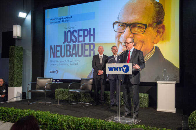 Joe Neubauer standing behind a WHYY podium giving a speech