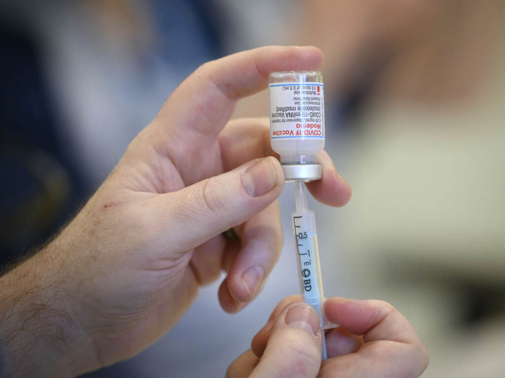 Medical staff and volunteers prepare shots of the Moderna COVID-19 vaccine