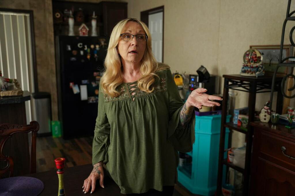 cheryl-gibson-spa-telehealth-121321-02 Cheryl Gibson gestures while standing inside her home