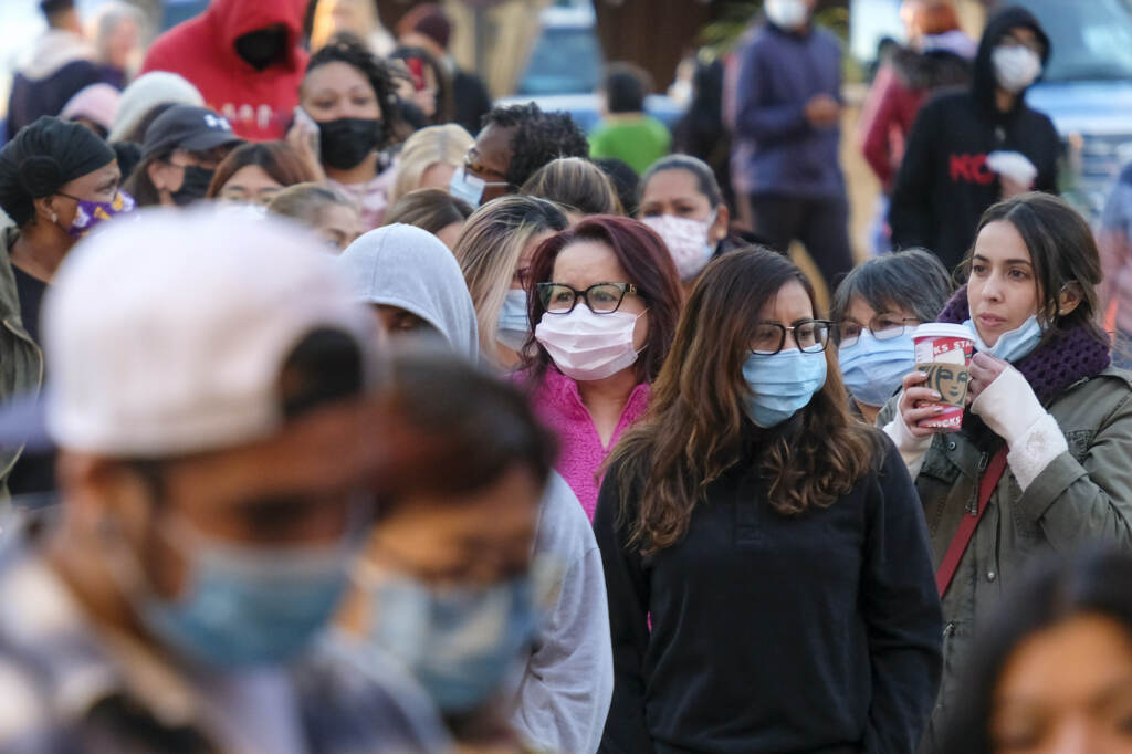 Black Friday Shopping Shoppers wearing face masks wait in line to enter a store