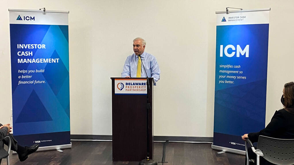 Fred Phillips stands at a podium with ICM banners on either side