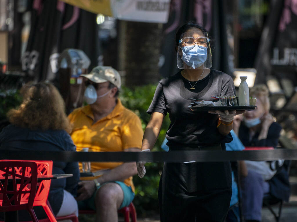 A waiter at Raku wears a face mask while serving customers outdoors