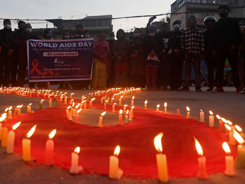 Volunteers stand after lighting candles in the shape of a red ribbon during an awareness event ahead of World AIDS Day in Kathmandu on Tuesday. Volunteers stand after lighting candles in the shape of a red ribbon during an awareness event ahead of World AIDS Day in Kathmandu on Tuesday. (Prakash Mathema/AFP via Getty Images)