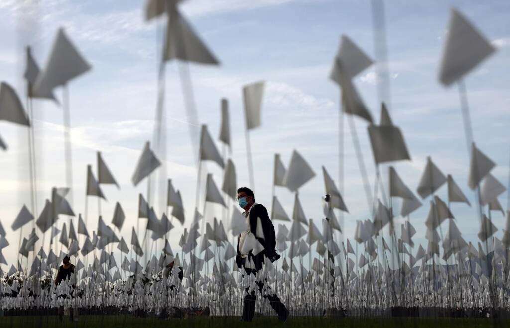gettyimagA person wearing a face covering walks past a white flag memorial installation outside Griffith Observatory honoring the nearly 27,000 Los Angeles County residents who have died from COVID-19 on Nov. 18 in Los Angeles, Calif.es-1354134169_custom-7ce0ecec454a99a64a2abaa3ddfaee148286e0e7-s1600-c85 A person wearing a face covering walks past a white flag memorial installation outside Griffith Observatory honoring the nearly 27,000 Los Angeles County residents who have died from COVID-19 on November 18, 2021 in Los Angeles, California. (Photo by Mario Tama/Getty Images)