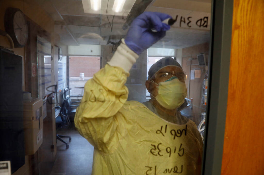 US Army Critical Care Nurse, Captain Edward Rauch Jr., writes on the door of a Covid-19 patient on a ventilator at Beaumont Hospital in Dearborn, Michigan on December, 17, 2021. Beaumont Hospital is assisted by 23 military medical personnel from the US Army, sent by the Department of Defense, to assist during the health system’s fourth Covid-19 surge. U.S. Army Critical Care Nurse Captain Edward Rauch Jr. writes on the room door of a COVID-19 patient