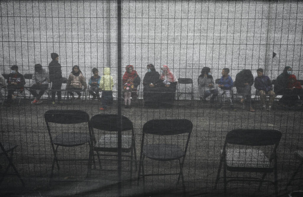 Afghan refugees queue outside a distribution and donation center