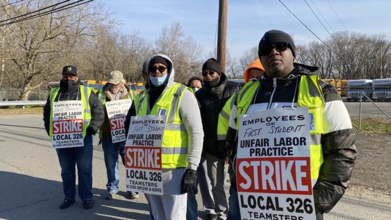 Striking bus drivers with Teamsters Local 326 stand outside the First Student bus yard