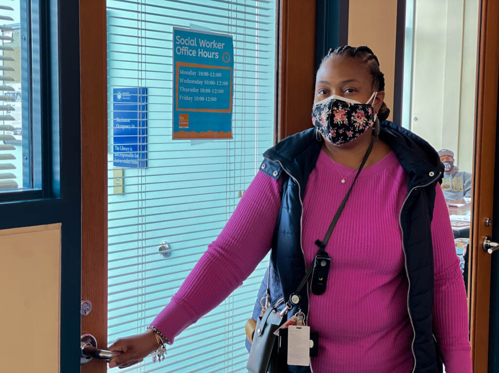 The Indianapolis Public Library hired Yanna McGraw as its first full-time social worker in July. Her job is to help library patrons navigate challenges beyond the scope of what librarians are trained to handle. Yanna McGraw holds her hand on a doorknob while wearing a mask