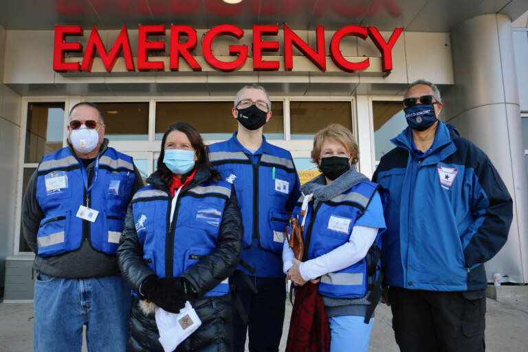 Volunteers from the Delaware County Medical Reserve Corps stand outside the Crozer Emergency Room, where they are needed to help the hospital cope with a flood of COVID-19 patients. They are (from left) Ken Barton, Marlynn Orlando, Georg Strey, Nancy Niemiec, and Dennis Daye.(Emma Lee/WHYY)