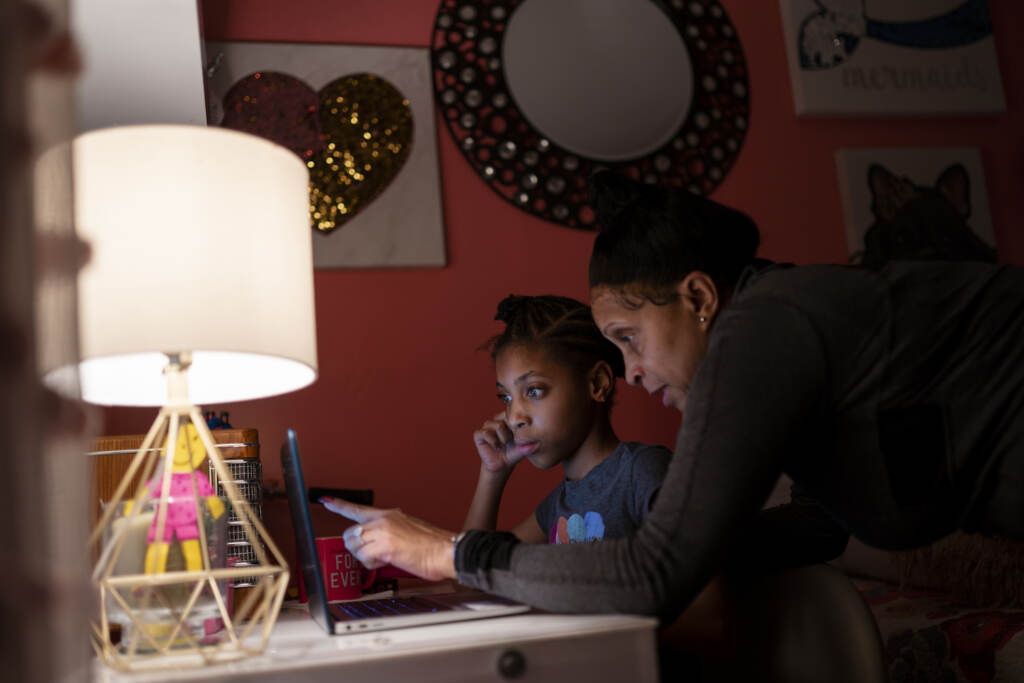 Virus Outbreak Digital Divide Abigail Schneider, 8, center, completes a level of her learning game with her mother April in her bedroom, Wednesday, Dec. 8, 2021, in the Brooklyn borough of New York.