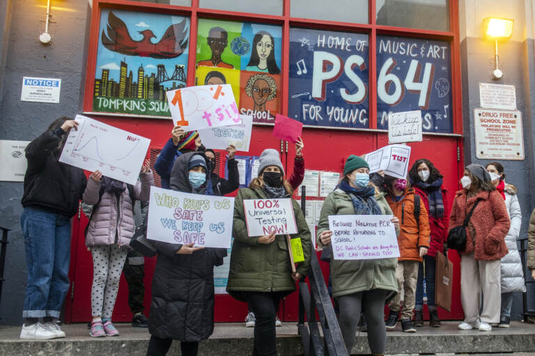 FILE — Teachers from the Earth School speak out on issues related to lack of coronavirus testing outside P.S. 64, Dec. 21, 2021, in New York. In the nation's largest school system, New York City, 2 million at-home test kits provided by the state will be used to increase testing following the break, the mayor announced this week. (AP Photo/Brittainy Newman, File)