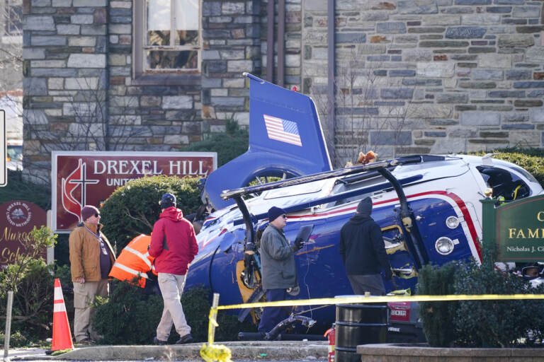 A medical helicopter rests next to the Drexel Hill United Methodist Church after it crashed in the Drexel Hill section of Upper Darby, Pa., on Wednesday, Jan. 12, 2022. Authorities and a witness say a pilot crash landed a medical helicopter without casualties in a residential area of suburban Philadelphia, miraculously avoiding a web of power lines and buildings as the aircraft fluttered, hit the street and slid into bushes outside a church.(AP Photo/Matt Rourke)