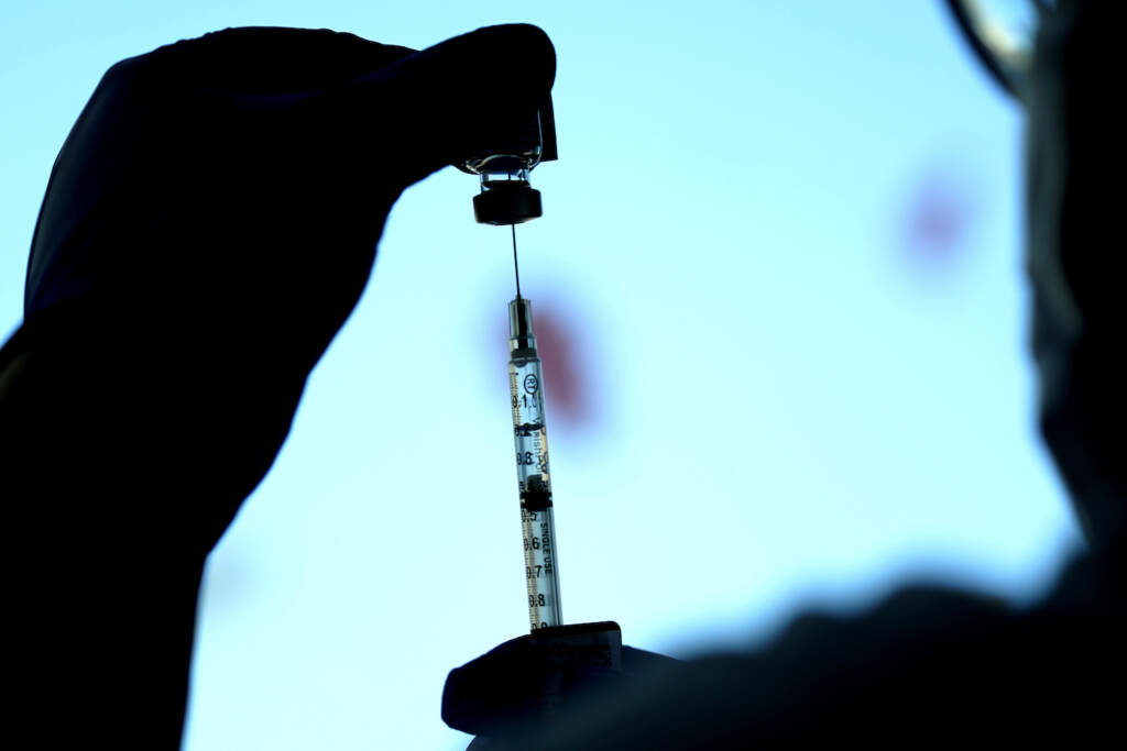 Melissa Balanon Silhouette of a COVID-19 vaccine being prepared.