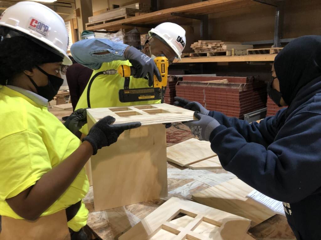 An experienced carpenter helps to CARP apprentices build a little free library (Emily Rizzo_WHYY) An experienced carpenter helps two CARP apprentices build a little free library.(Emily Rizzo/WHYY)