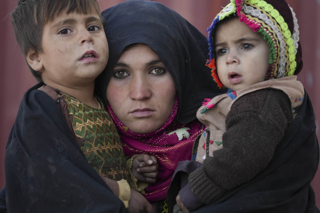 APTOPIX Afghanistan Downward Spiral An Afghan woman holds her children as she waits for a consultation outside a makeshift clinic organized by World Vision in an IDP settlement near Herat, Afghanistan, Thursday, Dec. 16, 2021. (AP Photo/Mstyslav Chernov)