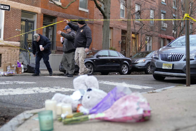Officials pass flowers and other items left in memory of victims of a fatal fire