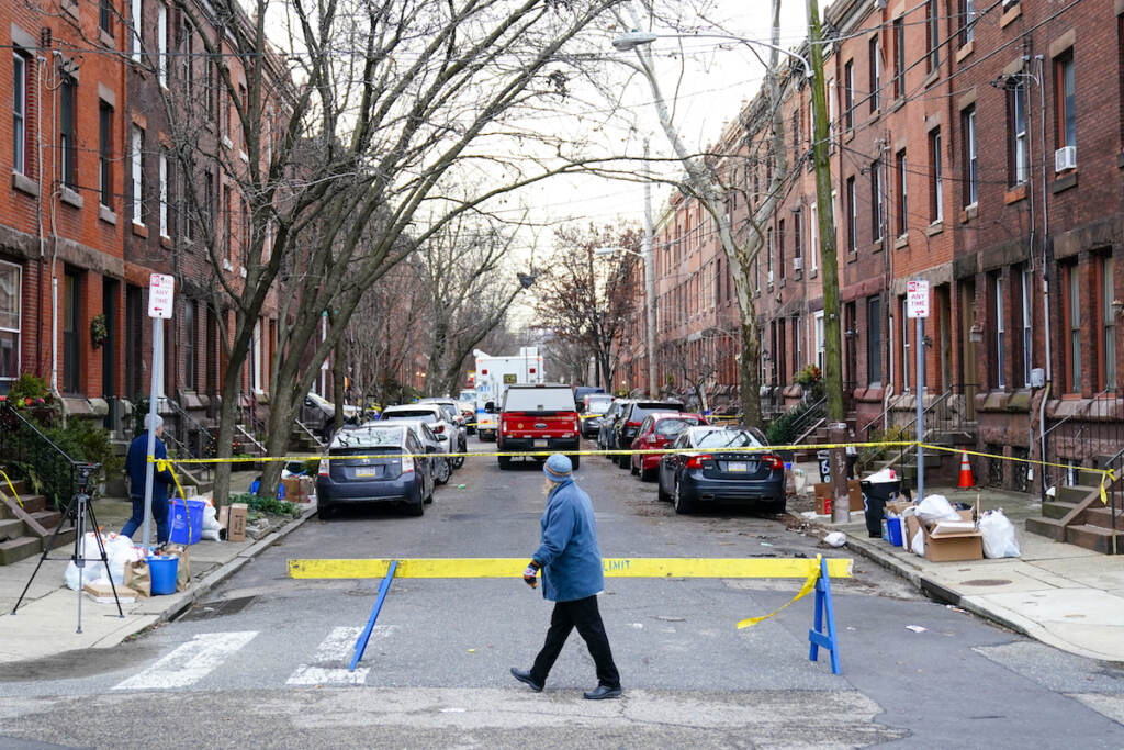 Philadelphia Fire A passer-by looks over the barricade on the street of Wednesday's deadly fire