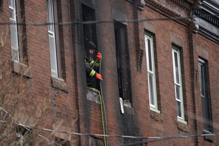A Philadelphia firefighter works at the scene of a deadly rowhouse fire