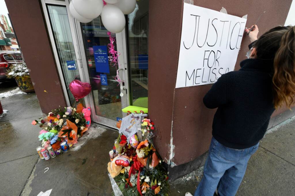 Karla Chavez, of the social activist group Chiactivists, puts up a sign at a memorial for 8 year old Melissa Ortega in Chicago on January 24, 2022. - Ortega was walking with her mother in Chicago's Little Village neighborhood on January 22 when she was struck by stray bullets after an unknown offender shot multiple times in their direction. (Photo by Paul Beaty / AFP) (Photo by PAUL BEATY/AFP via Getty Images)