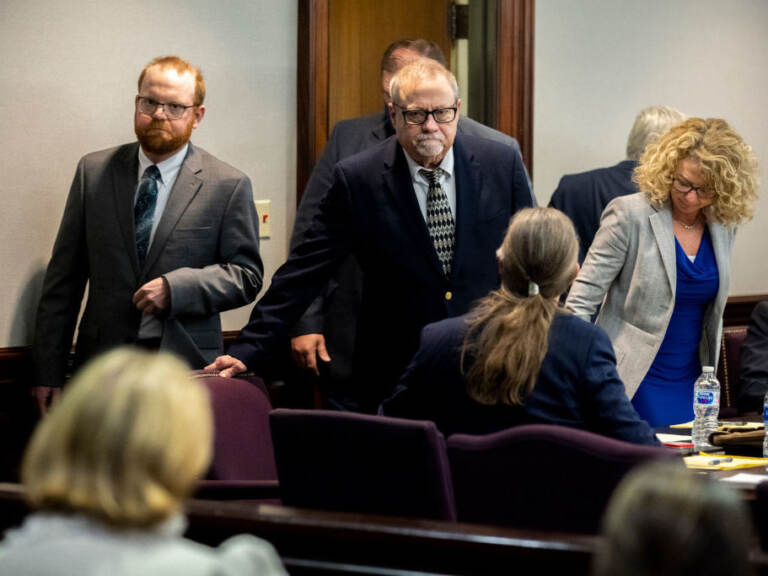 Greg McMichael, center, and his son, Travis McMichael, left, look at family members seated in the gallery when they walk into the courtroom