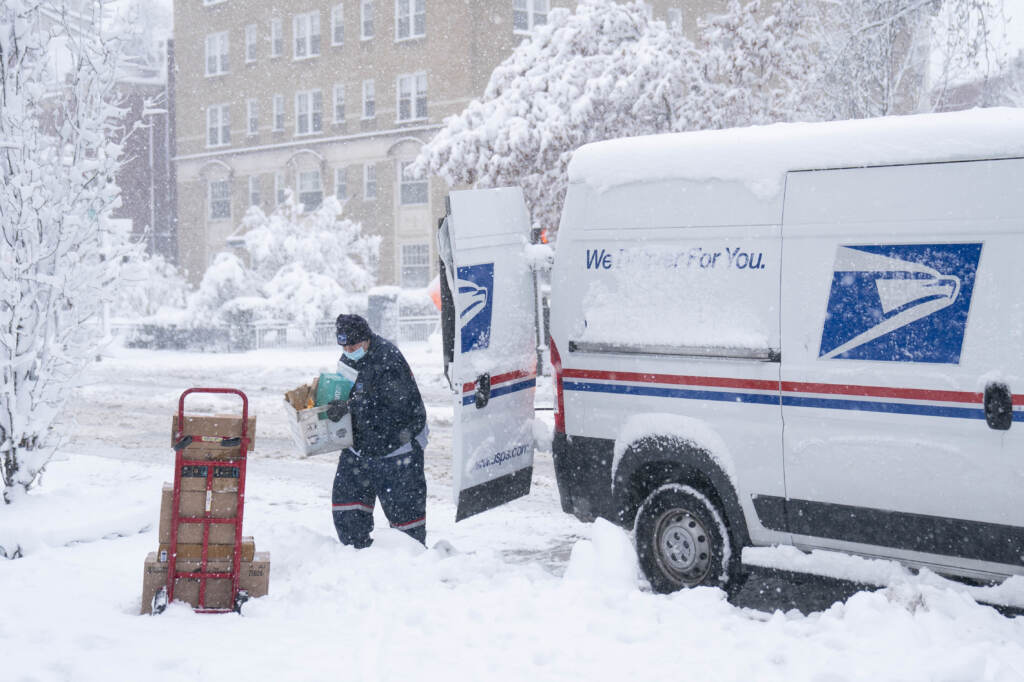 A postal worker carries packages through the snow on Jan. 3 in Washington, D.C. A postal worker carries packages through the snow