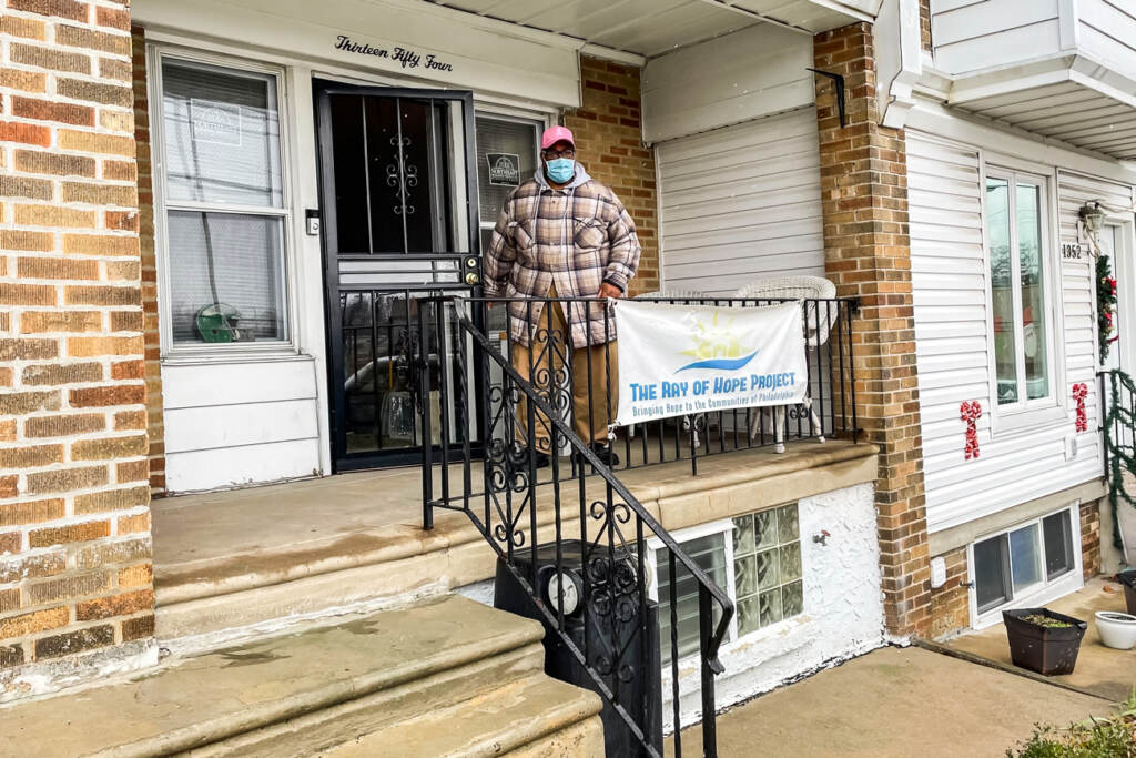 good-souls-GANT_ROH Raymond Gant standing on his porch with a sign for The Ray of Hope Project