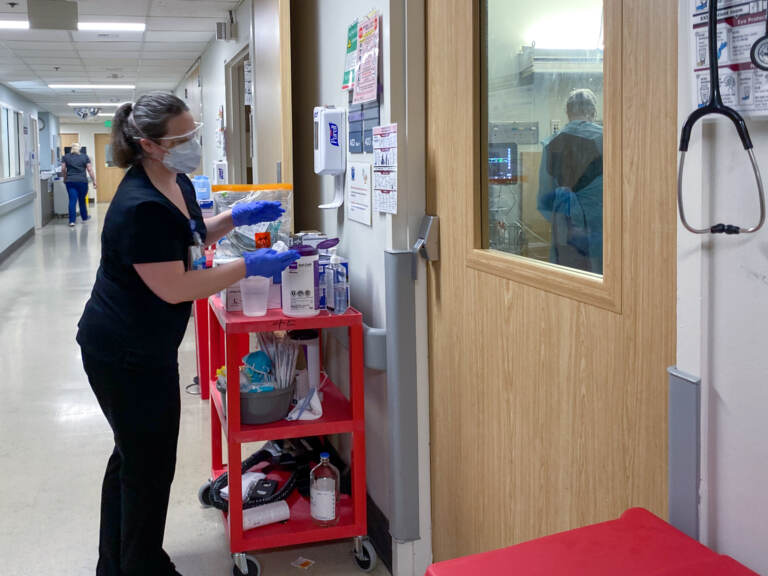 A health care worker peers into a COVID-19 patient's room. (Will Stone/NPR)