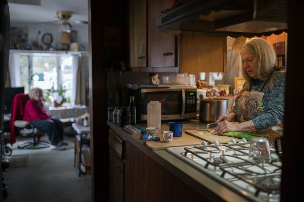 Virus Outbreak Long COVID Nancy Rose, right, cooks for her mother in the kitchen
